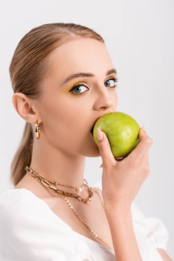 Sarışın kadın yeşil elmayı ısırıyor.