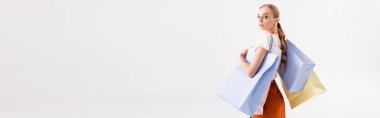 Beyaz panoramik kareye izole edilmiş alışveriş torbalarıyla zarif bir kadının yan görüntüsü