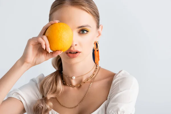elegant blonde woman with obscure face posing with orange isolated on white