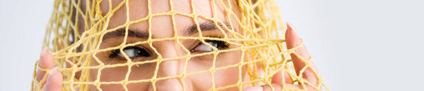 cropped view of woman looking through yellow string bag on white background, panoramic shot