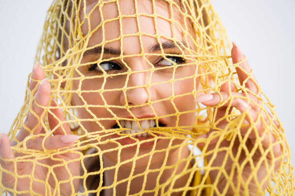 woman biting yellow string bag on white background