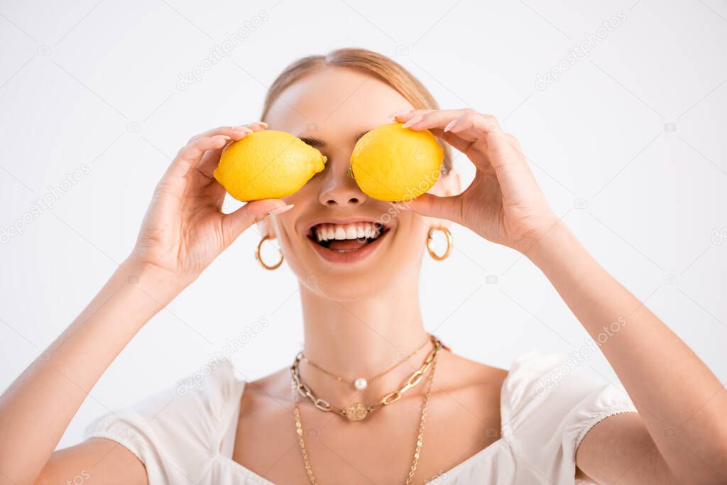 funny elegant blonde woman posing with lemons on eyes isolated on white