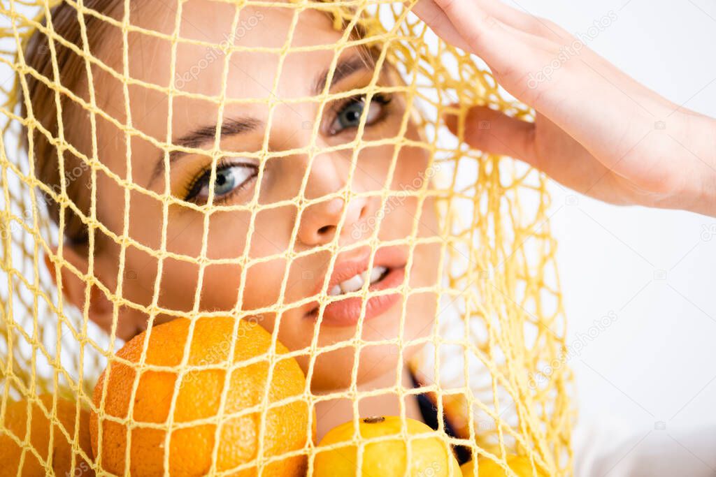 portrait of woman in string bag with citrus fruits