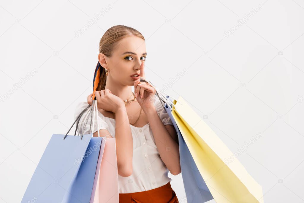 elegant woman with shopping bags showing shh sign isolated on white