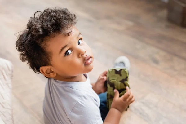 高高地观看卷曲的非洲裔美国小孩拿着玩具看着相机的情景 — 图库照片