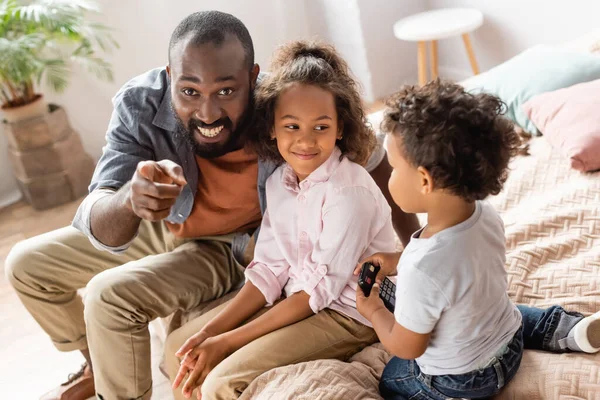 Excited African American Man Pointing Finger Children Sitting Bed — Stock Photo, Image