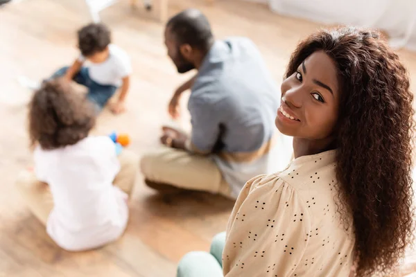 Enfoque Selectivo Mujer Afroamericana Mirando Cámara Cerca Familia Jugando Suelo — Foto de Stock