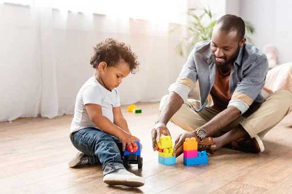 Ung Afrikansk Amerikansk Man Leker Med Byggstenar Golvet Med Lille — Stockfoto