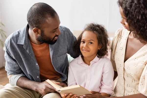 Africano Americano Chica Con Libro Mirando Cámara Mientras Sentado Cerca — Foto de Stock