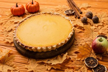 pumpkin pie with autumnal decoration on wooden background clipart