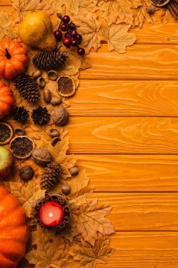 top view of burning candle with autumnal decoration on wooden background clipart