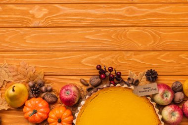 top view of thanksgiving pumpkin pie with autumnal decoration on wooden background clipart