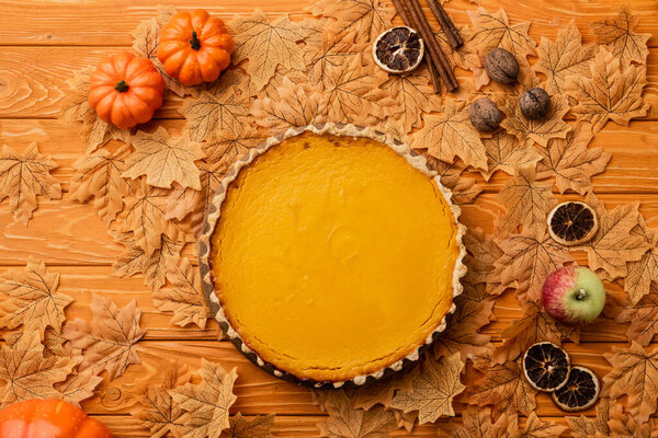 вид сверху на тыквенный пирог с осенним декором на деревянном фоне