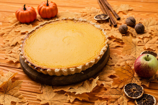pumpkin pie with autumnal decoration on wooden background