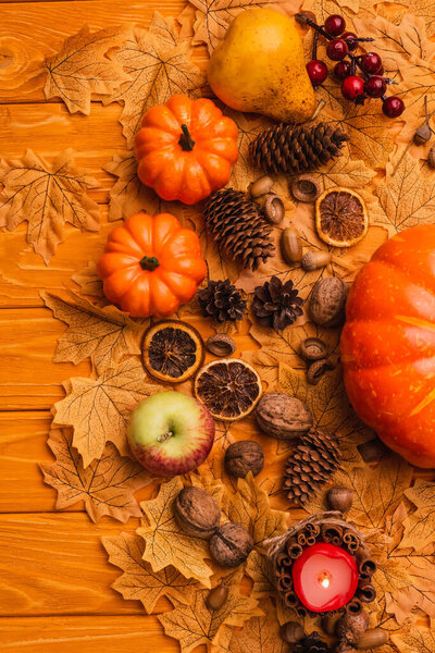 top view of burning candle with autumnal decoration on wooden background