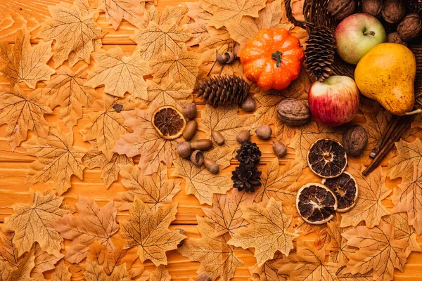 俯瞰秋天的装饰和从柳条篮散落在金黄色叶子上的木制背景的食物 — 图库照片
