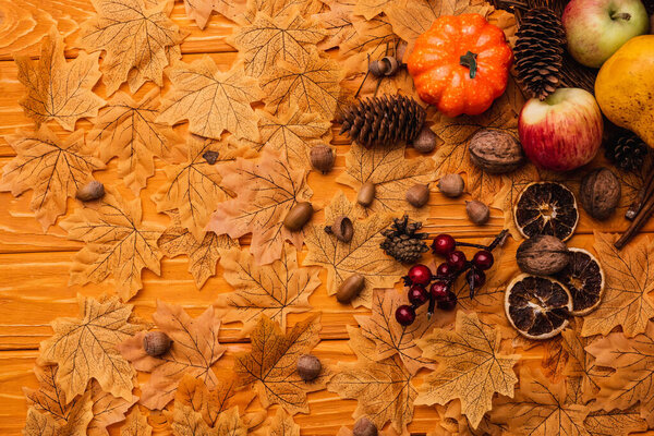 top view of autumnal decoration and food on golden foliage on wooden background