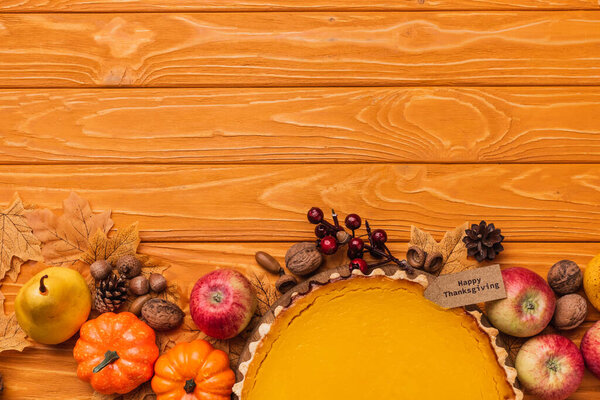 top view of thanksgiving pumpkin pie with autumnal decoration on wooden background