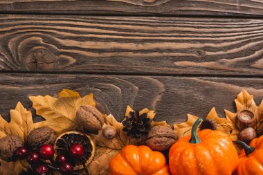 top view of autumnal decoration and pumpkins on brown wooden background clipart