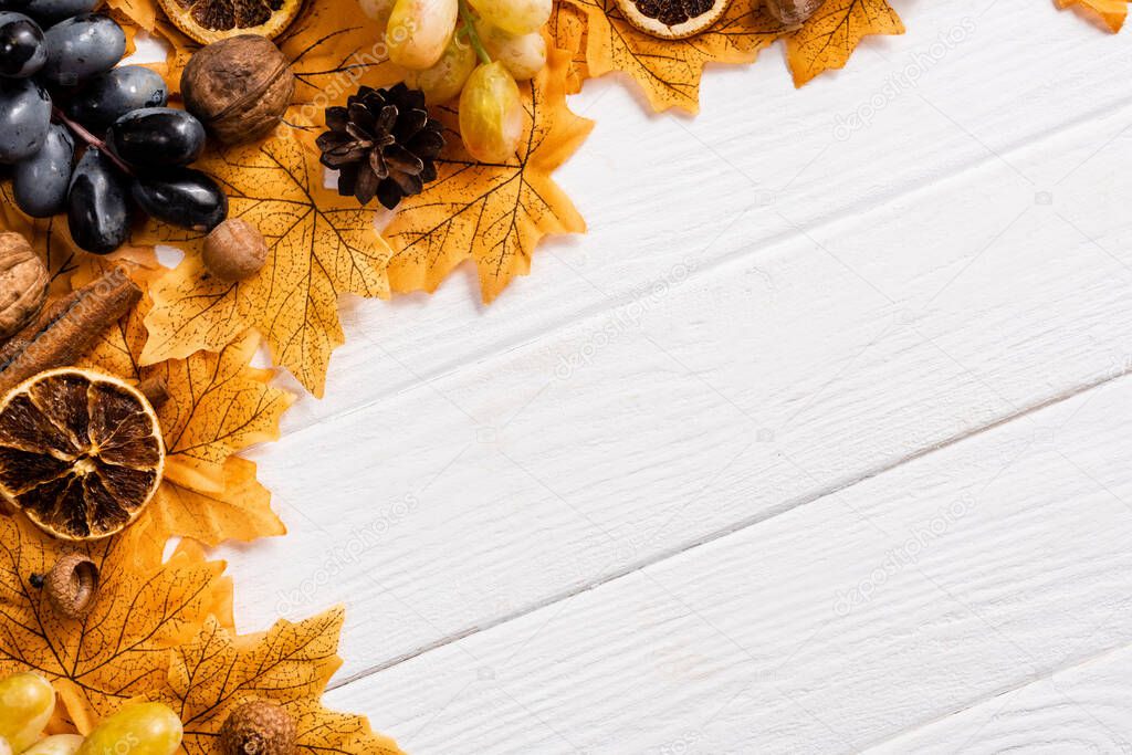 top view of autumnal decoration and grapes on white wooden background