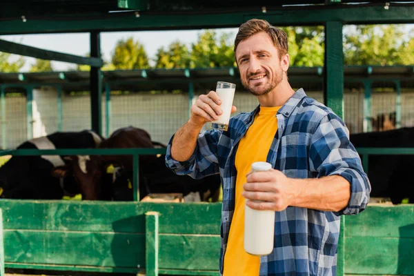 牛仔棚附近穿着格子花衬衫 手里拿着杯子和一瓶鲜牛奶的农民的选择焦点 — 图库照片