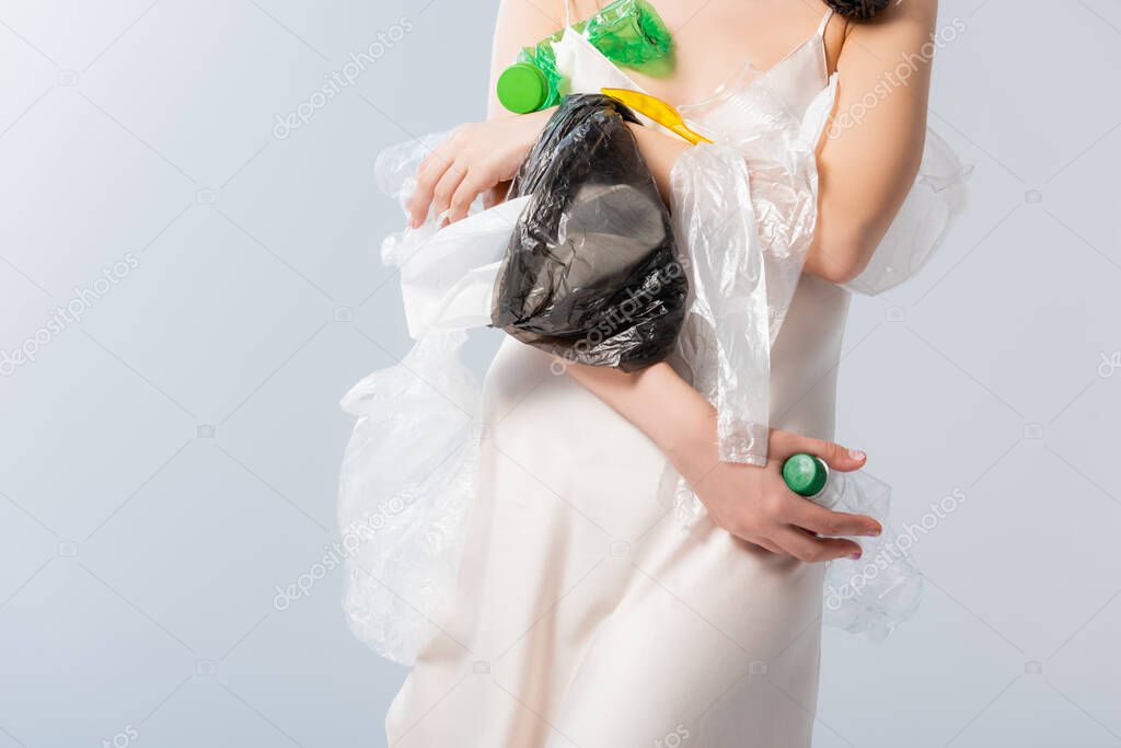 partial view of woman holding empty bottles and plastic bags on white, ecology concept  