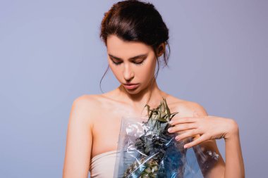 Polietilen içinde ananas tutan genç esmer kadın gri, ekoloji konseptinde izole edilmiş. 