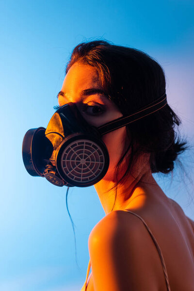 young and brunette woman in gas mask on blue