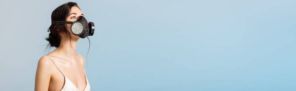 panoramic concept of brunette woman in gas mask looking up isolated on grey, ecology concept 