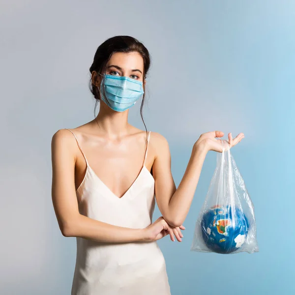의료용 마스크를 여성이 지구와 파란색 생태학적 개념을 플라스틱 가방을 있습니다 — 스톡 사진