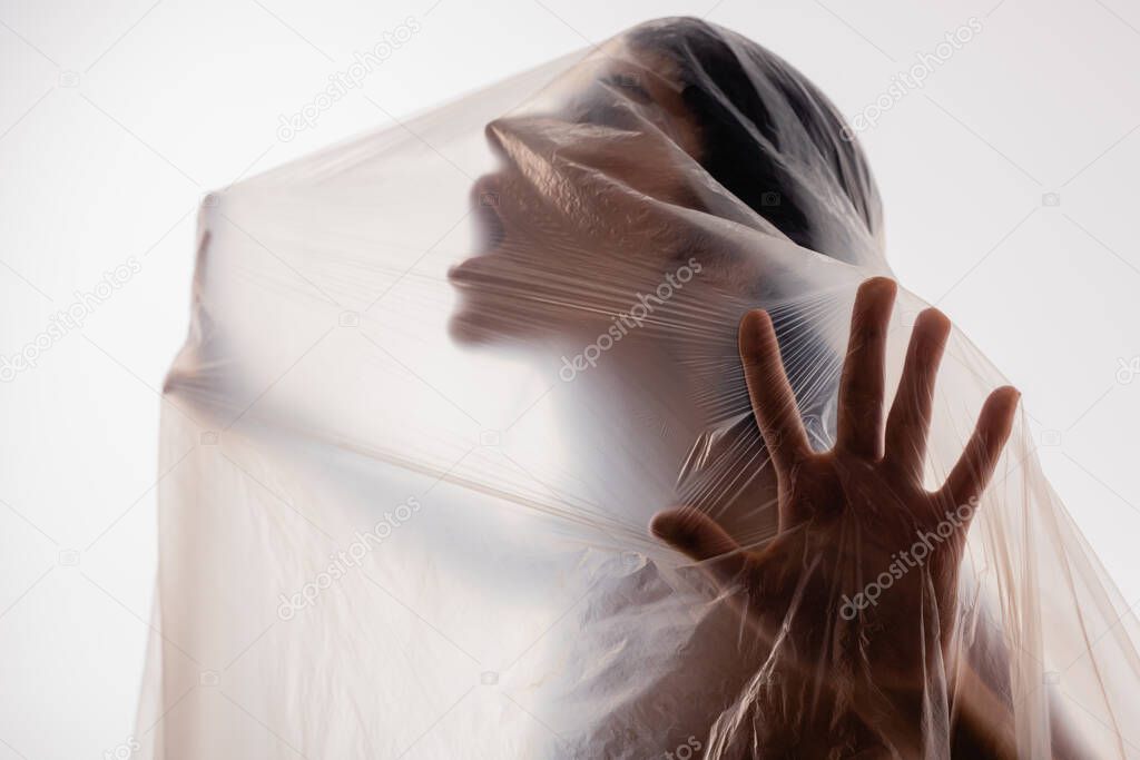 scared woman screaming through polyethylene isolated on white, ecology concept