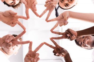 Bottom view of multiethnic volunteers showing peace gesture  clipart