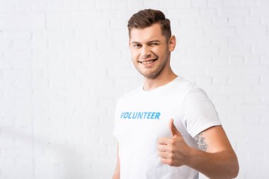 Gönüllü göz kırpıyor ve kameraya başparmağını gösteriyor 