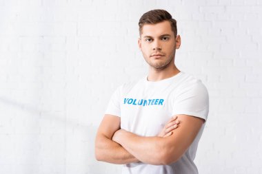 Kollarını kavuşturup kameraya bakan genç bir gönüllü. 
