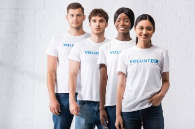 Çok kültürlü gönüllülerin seçmeli odak noktası tişörtler içinde kameraya bakan harflerle. 