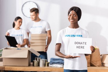 Afrika kökenli Amerikalı gönüllülerin seçici odak noktası, yardım derneğindeki harf bağışlarıyla eliyle kartı işaret ediyor. 