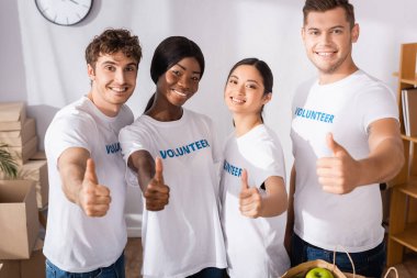 Multicultural volunteers showing like gesture in charity center  clipart
