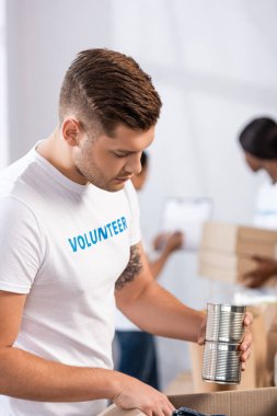 Genç gönüllülerin seçici odak noktası yardım merkezindeki kutulara konserve koymaları. 