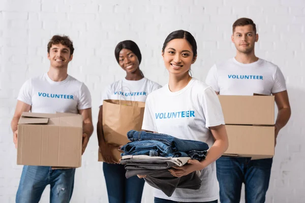 Enfoque Selectivo Mujer Asiática Sosteniendo Ropa Cerca Voluntarios Multiculturales Centro — Foto de Stock