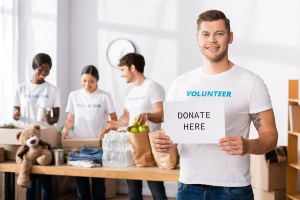 Enfoque Selectivo Tarjeta Retención Jóvenes Voluntarios Con Donar Aquí Letras — Foto de Stock