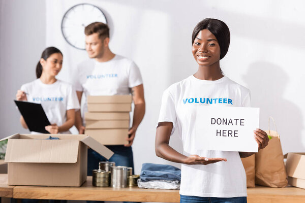 Селективный фокус африканского волонтера, указывающего рукой на карту с пожертвованием здесь буквами в благотворительном центре 