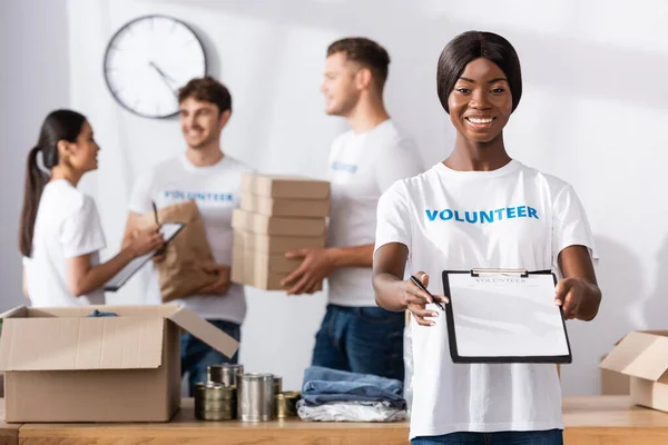 Enfoque Selectivo Del Voluntario Afroamericano Mostrando Portapapeles Bolígrafos Cerca Donaciones — Foto de Stock