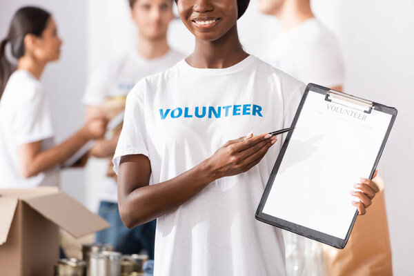 Selective focus of african american volunteer pointing at clipboard in charity center 