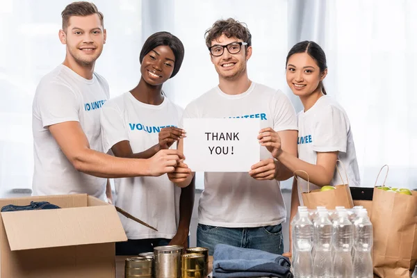 Voluntarios Multiculturales Con Tarjetas Agradecimiento Junto Latas Ropa Paquetes Mesa — Foto de Stock