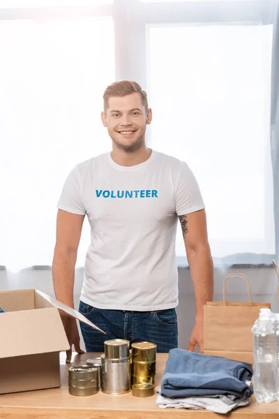 Selective Focus Volunteer Looking Camera Tin Cans Clothes Carton Box — Stock Photo, Image