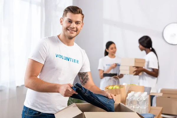 Selective Focus Volunteer Looking Camera While Putting Clothes Cardboard Box — Stock Photo, Image