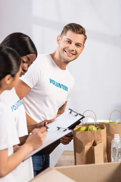 Enfoque Selectivo Del Voluntario Mirando Cámara Cerca Mujeres Multiétnicas Con — Foto de Stock