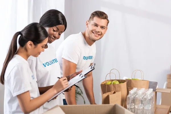 Selective Focus Volunteer Looking Camera Multicultural Women Clipboards Packages Charity — Stock Photo, Image