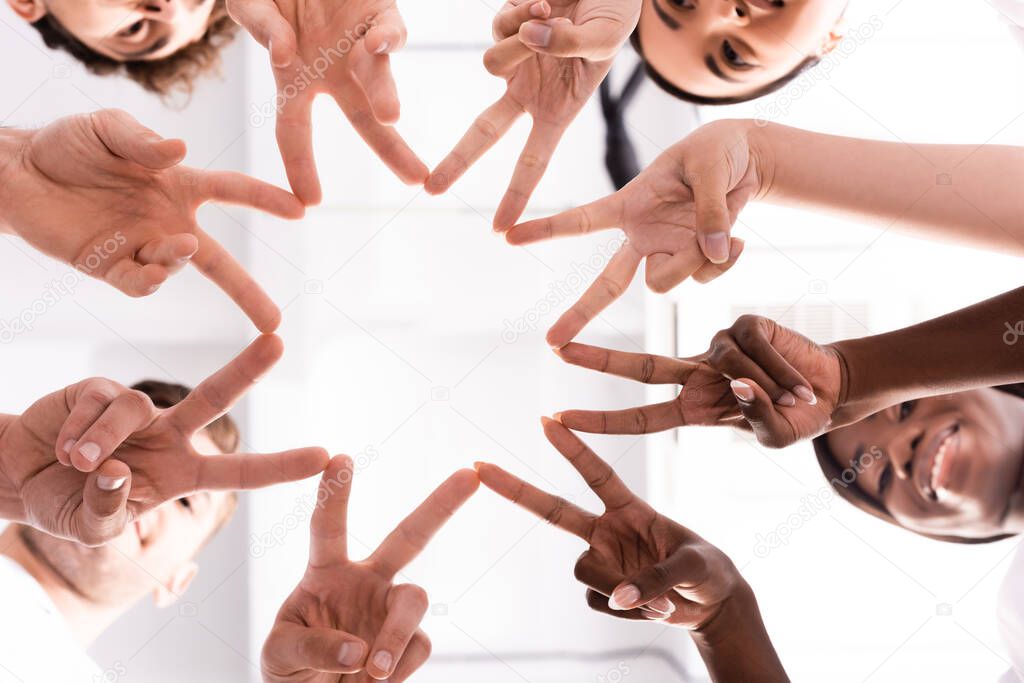 Bottom view of multiethnic volunteers showing peace gesture 