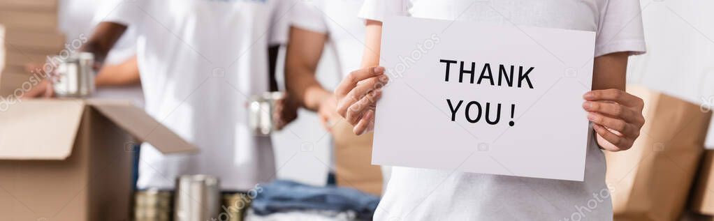 Panoramic crop of woman holding card with thank you lettering in charity center 